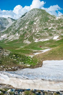 Kuzey Karadağ 'ın pitoresk yüksek dağlık turizm yolunun geçtiği Durmitor Milli Parkı' nın zirveleri ve karları. UNESCO Dünya Mirası sitesi. Güzel yaz güneşli ve bulutlu manzara.