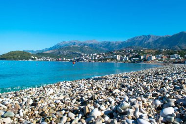 Himare 'nin dağların eteğindeki güzel çakıl taşı plajı. Adriyatik Denizi. Arnavutluk. Yaz bulutu manzarası. Yaz tatili ve rahatlama kavramı.