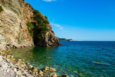 Halka açık kumsalda güzel kayalar. Rafailovici Esort kasabaları. Dağlı. Adriyatik Denizi. Yaz güneşli bir gün. Deniz kenarı tatil kavramı. 