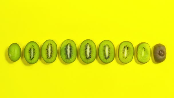 4Kブラウンキウイフルーツはスライスに分かれています キウイスライスラインアップ 黄色の背景 コピースペース コピースペース 適切な栄養と健康的な果物の概念 ストップモーションアニメーション — ストック動画