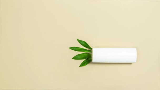 Белый Тюбик Косметическим Кремом Бежевом Фоне Зеленые Листья Прорастают Трубки — стоковое видео