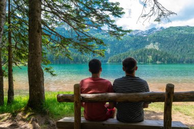 Buzul Kara Göl yakınlarındaki ahşap bir bankta turistler. Durmitor Ulusal Parkı 'nın turistik merkezi. Gölü çevreleyen yürüyüş yolu eğlence ve yürüyüş için popüler bir yerdir. Karadağ