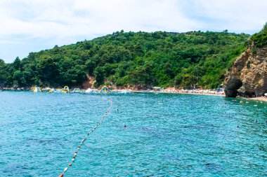 Kumlu Morgen Sahili 'nin güzel dağ manzarası şişirilebilir eğlence suyu cazibesiyle. Budva şehrinin yakınında bir sahil. Yaz mevsimi. Karadağ.