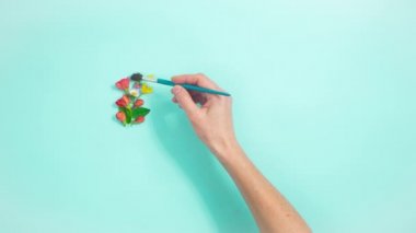 4k Kadın 'ın eli, doğal çiçeklerden, tomurcuklardan ve açık mavi arkaplandaki taze yapraklardan kopyalanmış bir şekilde daire çiziyor. Bahar ve yaz konsepti. Hareket animasyonunu durdur. Düz yatıyordu.