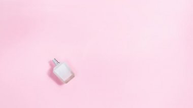 4k Natural single lilac flowers sprayed from a white perfume bottle. Symbol of beautiful floral aromas and the smell of perfume. Light blue background with copy space. Stop motion animation. Flat lay.