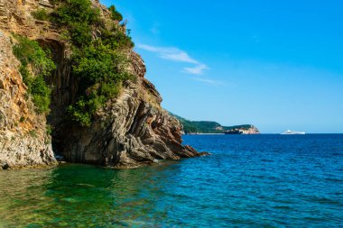 Halka açık kumsalda güzel kayalar. Rafailovici Esort kasabaları. Dağlı. Adriyatik Denizi. Yaz güneşli bir gün. Deniz kenarı tatil kavramı.