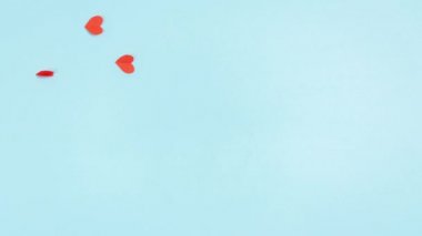 4k Red paper hearts fly like butterflies to woman's hand. Fly into an envelope that closes and flies through clouds. Blue background. Love messages concept. Stop motion animation. Copy space. Flat lay