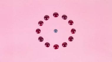4k Berry kaleidoscope. Fireworks from ripe blueberries, cherries and plums appearing in the center. Concept of berries season and proper nutrition. Pink background. Flat lay. Stop motion animation.