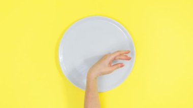 Woman's hand snaps her fingers and pizza appears on an white plate, then pizza slices disappear and everything repeats again. Yellow background. Popular delicious food concept. Stop motion animation.