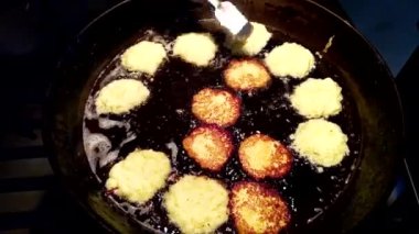 On a large black frying pan, the chef fries draniki (potato pancakes), a popular dish of European cuisine made from grated potatoes, which are an essential attribute of Belarusian cuisine.
