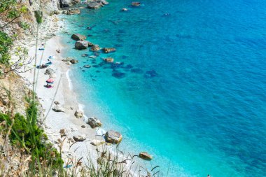 Sadece denizden ulaşılabilen dik kayalıklarla çevrili küçük çakıl taşı Filikuri plajı. İyon Denizi. Arnavutluk. Üst Manzara. Yaz güneşli mavi manzara.
