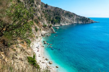 Sadece denizden ulaşılabilen dik kayalıklarla çevrili küçük çakıl taşı Filikuri plajı. İyon Denizi. Arnavutluk. Üst Manzara. Yaz güneşli mavi manzara.