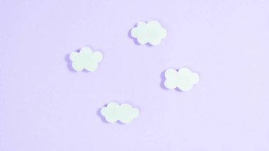 Açık mor arkaplanda beyaz kağıt bulutlar. Minimalizm, kopyalama alanı. Tasarım ve metin şablonu. 