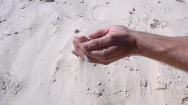 Kuru kum, erkeklerin ellerinden dökülür. Açık kumlu arka plan. Zamanın geçişi ve kaçırılan fırsatlar kavramı.. 