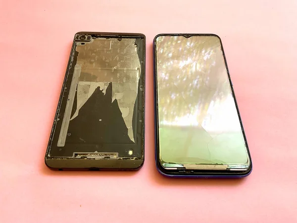 Damaged and Broken Screen Mobile Phones on Pink Background