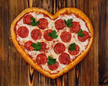 Restoran menüleri için ahşap arka planda kalp şeklinde pizza.