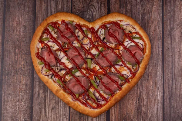 Restoran menüleri için ahşap arka planda kalp şeklinde pizza.