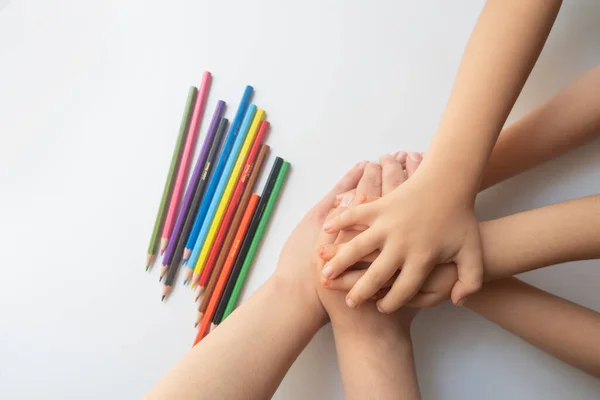 Crayons and four children\'s hands on a white background. education concept.Concept of kinder education during the pandemic period.