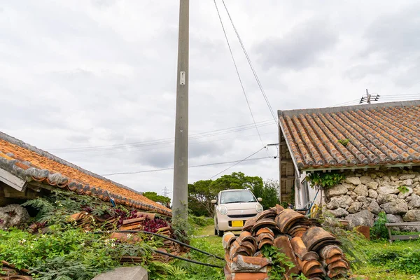 Japonya 'nın Okinawa kırsalında bulutlu bir günde çekilmiş bir tuğla, araba ve ev fotoğrafı.