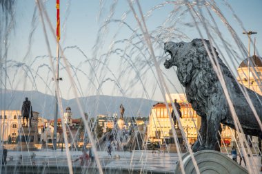 Arkaplanda Büyük İskender 'i tasvir eden su çeşmesi ve heykellerin olduğu birkaç aslandan biri olan aslan heykeli. Gün batımından hemen önce..