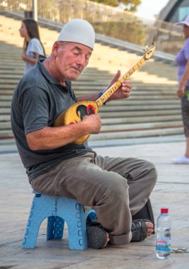 Yaşlı adam, Üsküp 'ün Eski Çarşı bölgesinin dışında oturan geleneksel bir telli çalgıyla müzik çalıyor.