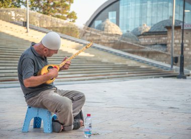 Yaşlı adam, Üsküp 'ün Eski Çarşı bölgesinin dışında oturan geleneksel bir telli çalgıyla müzik çalıyor.