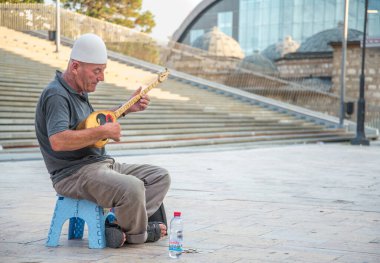 Yaşlı adam, Üsküp 'ün Eski Çarşı bölgesinin dışında oturan geleneksel bir telli çalgıyla müzik çalıyor.