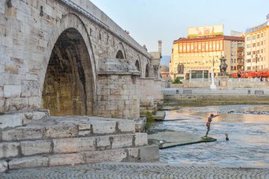 SKOPJE, NORTH MACEDONIA-AĞUSTOS 28. 2018: Yeni modern bronz bir kadın, taş köprünün altında heykel yapmak üzere Vardar Nehri 'ne dalmak üzere gibi görünüyor..