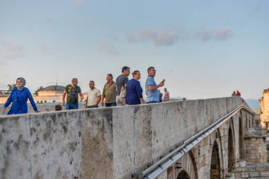 SKOPJE, NORTH MACEDONIA-AĞUSTOS 28. 2018: Yayalar Üsküp 'ün ana simgesi olan Taş Köprü' de bir ileri bir geri yürüyor.