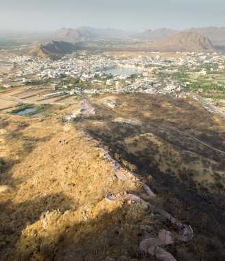 Uzakta görülen Pushkar Gölü, Hindular için popüler bir hac alanı olan Ratnagiri Tepesi 'nde bulunan tapınaktan inen uzun yol olarak görülüyor..