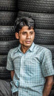 KOLKATA, Batı BENGAL / INDIA-MARCH 19 2018: Bir araba lastiği satıcısı müşteri bekleyen lastik yığınlarının önünde oturur.
