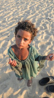 CHENNAI, TAMIL NADU / INDIA-MARCH 2. 2018: Genç bir kız çocuğu Marina sahilinin kumları boyunca para dileniyor.