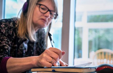 Kulaklıkla canlı yayında yayınlanan web tabanlı bir siminarı dinlerken not almak.