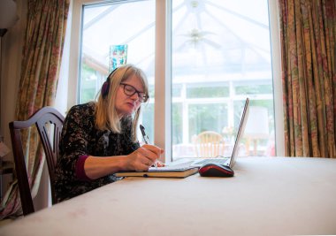 Kulaklıkla canlı yayında yayınlanan web tabanlı bir siminarı dinlerken not almak.