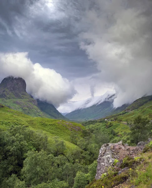 Low cloud quickly rolling in,after sunset, along the beautiful green valley of Glen Coe,clinging to the mountain tops,in mid-summer,causing ever changing light,typical of the Highlands of Scotland.