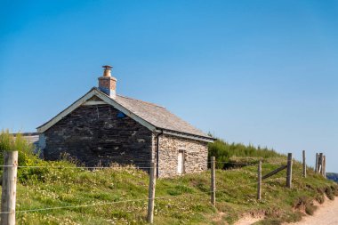 Cornwall, İngiltere, İngiltere-20 Temmuz 2021: Kumlu bir patika, yaz ortasında Atlantik 'teki Booby Körfezi' ne uzanan küçük bir taş kulübenin yanından geçer...