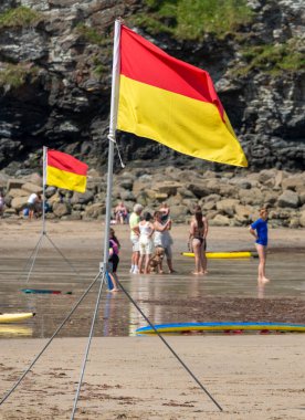 St.Agnes, Cornwall, İngiltere, İngiltere, 22 Temmuz: RNLI üyeleri tarafından tripoda dikilmiş bir deniz güvenliği bayrağı, güzel bir yaz gününde önerilen yüzme alanının cankurtaranlarla dolu olduğunu gösteren renkler gösteriyor.