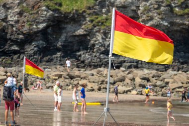 St.Agnes, Cornwall, İngiltere, İngiltere, 22 Temmuz: RNLI üyeleri tarafından tripoda dikilmiş bir deniz güvenliği bayrağı, güzel bir yaz gününde önerilen yüzme alanının cankurtaranlarla dolu olduğunu gösteren renkler gösteriyor.