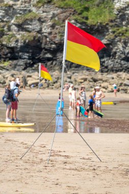 St.Agnes, Cornwall, İngiltere, İngiltere, 22 Temmuz: RNLI üyeleri tarafından tripoda dikilmiş bir deniz güvenliği bayrağı, güzel bir yaz gününde önerilen yüzme alanının cankurtaranlarla dolu olduğunu gösteren renkler gösteriyor.