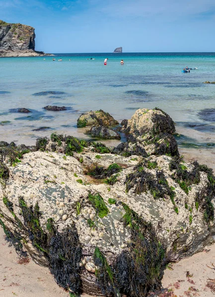 英国康沃尔圣艾格尼丝 在一个阳光灿烂 炎热的仲夏 度假者们享受着大西洋温暖的海水 在这个受欢迎的旅游胜地 一个巨大的巨石矗立在悬崖边 — 图库照片