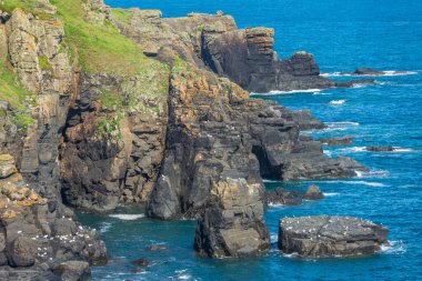 Güzel, açık, güneşli yaz havası, çimen çiçekli uçurumlar, sakin denizler, dramatik kıyı şeridi, İngiliz anakarasının en güney noktası. Kertenkele Köyü yakınlarında popüler bir turizm beldesi..