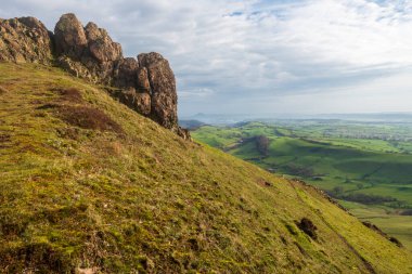Gün doğumunda Shropshire kırsalına bakan dev kayalar, kayalık araziler ve tepeleri kaplayan çimenler, rüzgarlı tepenin dramatik manzarası..