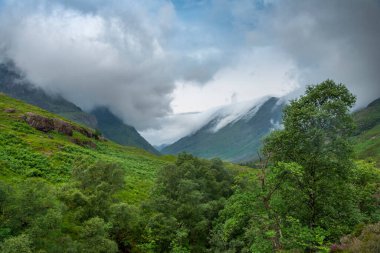 Early evening post sunset clouds roll in quickly, along the beautiful green valley,during the summer,a distant white cottage within the dramatic landscape,causing ever changing lighting conditions.