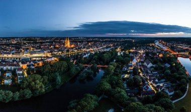 Tuna nehri ile Bavyera 'daki Regensburg şehrinin panoraması aydınlanmış katedral ve Almanya' nın alacakaranlık saatinde yazın mavi saatte taş köprü.