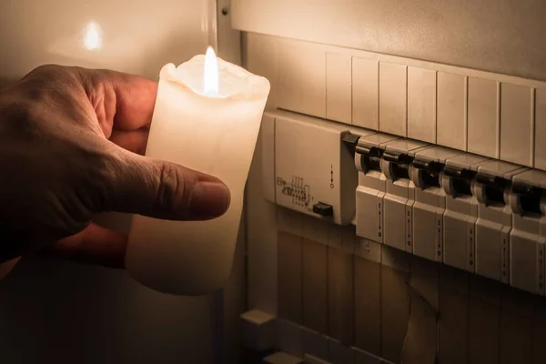 ドイツの男性が保持する白いろうそくで照らされた停電の間 配電ボックス内のヒューズ付きヒューズボックス — ストック写真