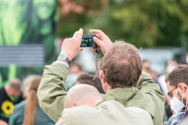 Regensburg, Bavaria, Germany, 18. August 2021, A man in the audience takes a picture of campaign appearance of Annalena Baerbock of the German party Buendnis 90 - die Gruenen for the 2021 federal election, Germany