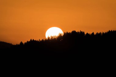 Gün batımında ufukta güneş batarken, Almanya 'da, önplandaki dağ manzarası ile birlikte.