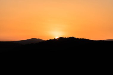 Gün batımında ufukta güneş batarken, Almanya 'da, önplandaki dağ manzarası ile birlikte.