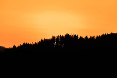 Gün batımında ufukta güneş batarken, Almanya 'da, önplandaki dağ manzarası ile birlikte.