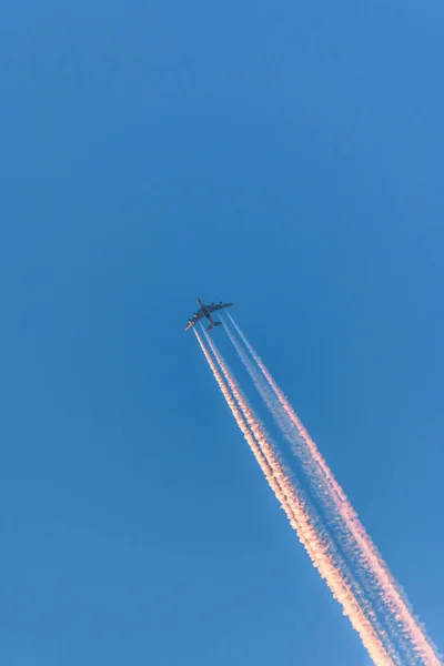 Samolot Błękitnym Bezchmurnym Niebie Kolorowymi Smugami Bez Chmur Podczas Zachodu — Zdjęcie stockowe